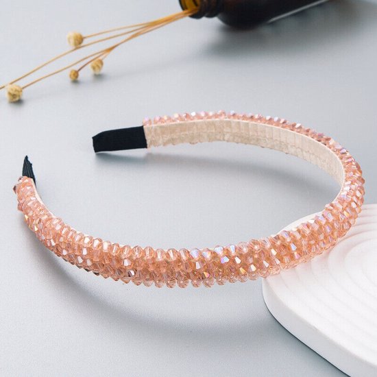 Lichtroze haarband versierd met glinsterende strass steentjes op een neutrale achtergrond.