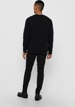 Man met zwarte sweater, van achteren gezien.