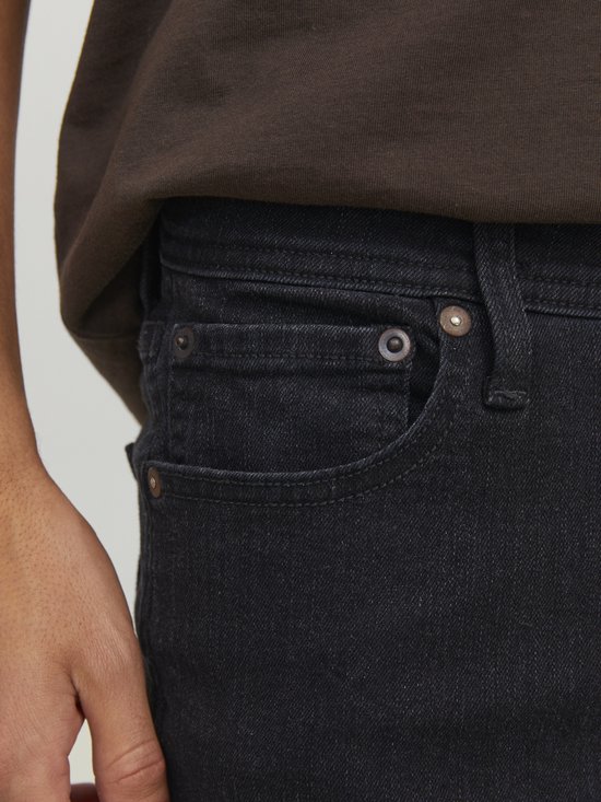 Sluiting van de zwarte denim jeans met zakken en klinknagels.