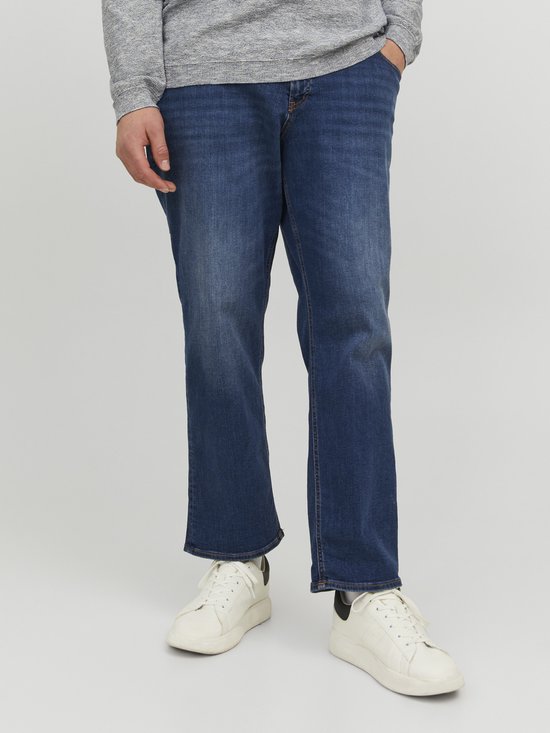 Man met blauwe jeans, grijze trui en witte sneakers.