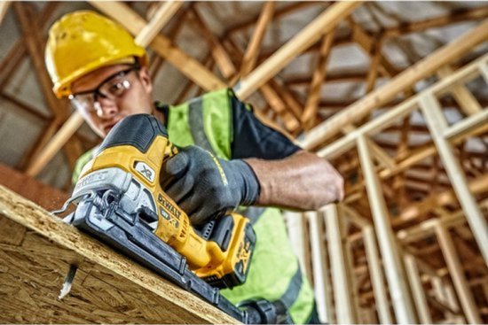 Een bouwmedewerker snijdt een plank met een DeWalt decoupeerzaag.