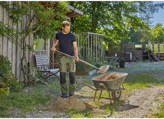 Een man in een groen tuinbroek vult een kruiwagen met zand met een grijze schop met turquoise accent.