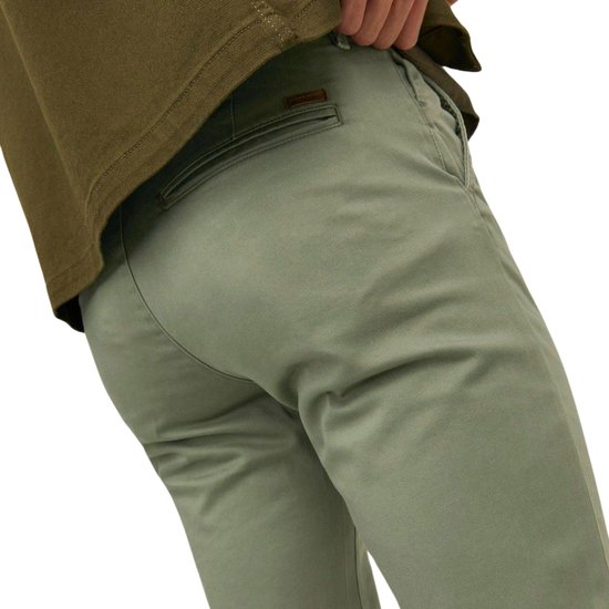 Achterkant lichtgroene chino met bruine label.