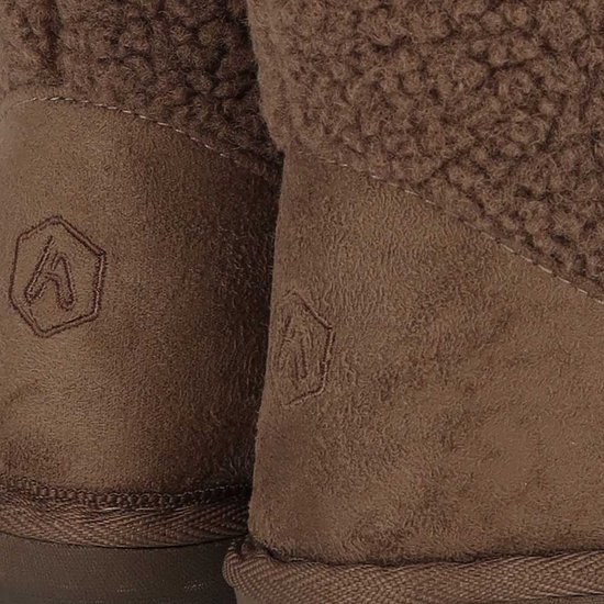 Close-up van de beige suède hiel met subtiel ingedrukt logo op donkerbruine teddy enkellaars pantoffels.