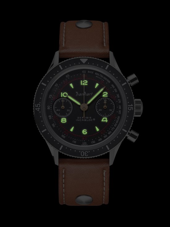 Hanhart horloge met lichtgevende wijzers en indexen op een zwarte wijzerplaat, met bruine band.