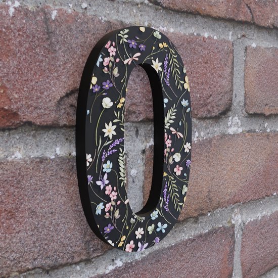 Huisnummer 0 met een zwart fond en een kleurrijk bloemenprint met paarse, gele en roze bloemen en groene bladeren, op een bakstenen muur.