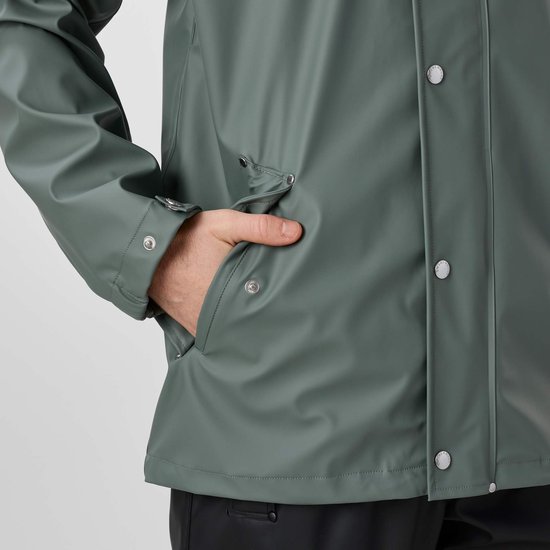 Gedetailleerde opname van een hand in de zak van een groene jas.