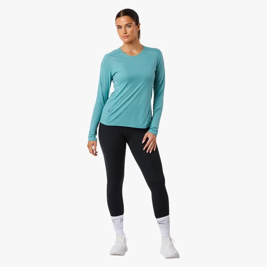 Vrouw in turquoise sportshirt met lange mouwen en zwarte legging, merk Swedemount.