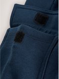 Close-up van de klittenbandsluitingen op de cargo zakken van een marineblauwe joggingbroek.