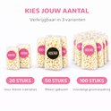 Transparante blokbodem traktatiezakjes met 'HOERA!' sticker, gevuld met popcorn. Getoond in 3 verpakkingen: 20, 50 en 100 stuks.