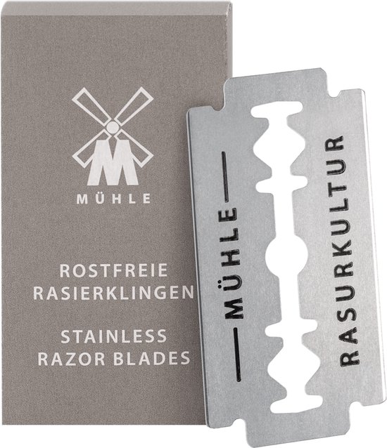 Een MÜHLE roestvrije scheermesje met "RASURKULTUR" erop, naast een doosje met het "M" logo, "ROSTFREIE RASIERKLINGEN" en "STAINLESS RAZOR BLADES".