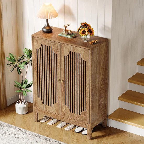 Houten schoenenkast met gesloten lamellendeuren en twee gouden handgrepen, met een lamp, hertje en zonnebloemen bovenop.