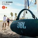 Zwarte JBL Charge 6 speaker op een strand, met een tekst over 28 uur afspeeltijd.