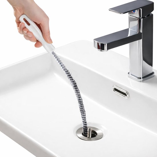 Grijze flexibele ontstoppingsveer met wit handvat, vol met haar, in een witte wasbak.