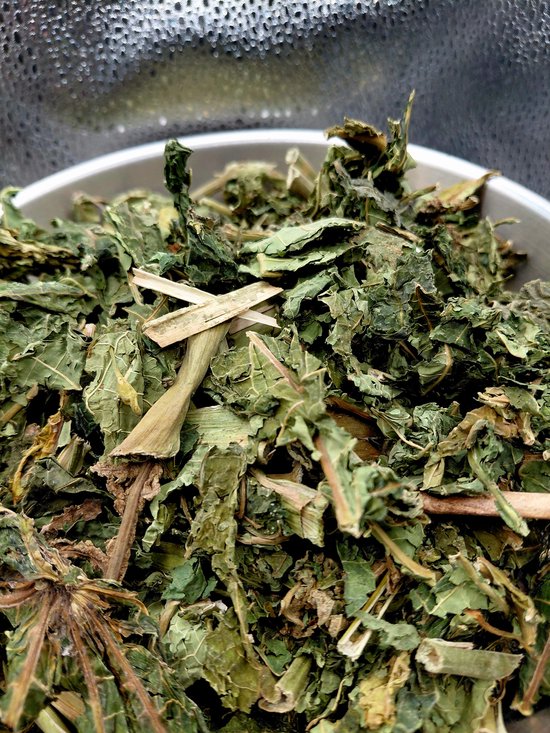 Gedroogde papayabladeren, groen en bruin, in een metalen kom.
