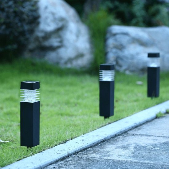 Rij van drie zwarte, vierkante tuinlampen met geribde glazen kappen, geplaatst langs een gazon.