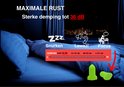 Twee felgroene oordopjes op een dekbed, met op de achtergrond een bed in de nacht. "MAXIMALE RUST"
