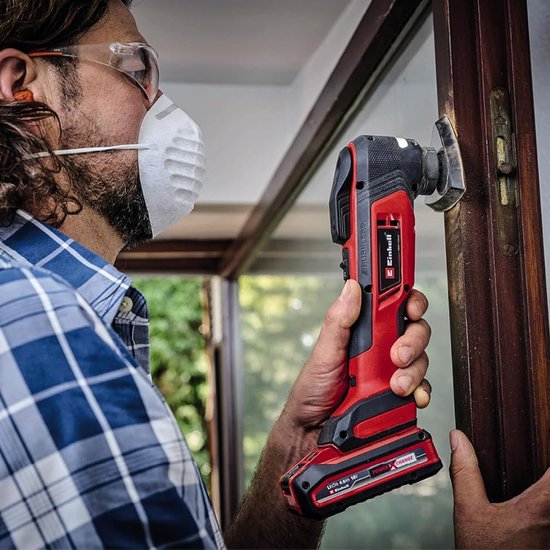 Man met rood-zwarte multitool werkt aan een houten raamkozijn.