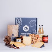 Een borrelpakket met kazen, worst, crackers, sap en jam, met een papieren zak en een geschenkdoos.