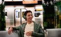 Man met groene koptelefoon lachend op een metrostation.