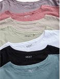 Close-up van de ronde halzen en neklabels van gestapelde T-shirts in verschillende kleuren: zwart, wit, beige, lichtgroen, oudroze en grijs.
