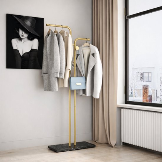 Gouden kapstok met marmeren voet, met kleding en tas eraan. Naast een schilderij van een vrouw met hoed.