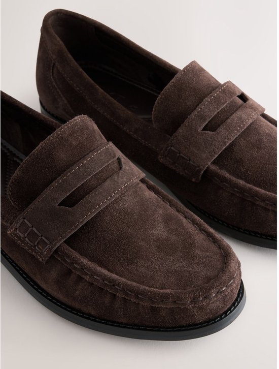 Bovenkant van bruine suède loafers met dubbele banden en stiksels.