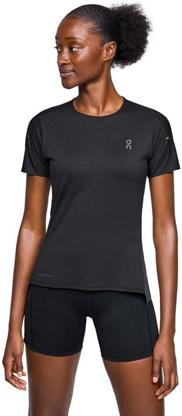 Model met zwarte ON Running performance T-shirt met korte mouwen en korte broek. Het shirt heeft een logo op de borst.