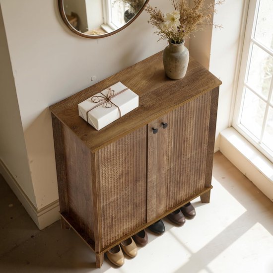 Houten schoenenkast met gesloten deuren, een pakje, vaas met bloemen en schoenen eronder.