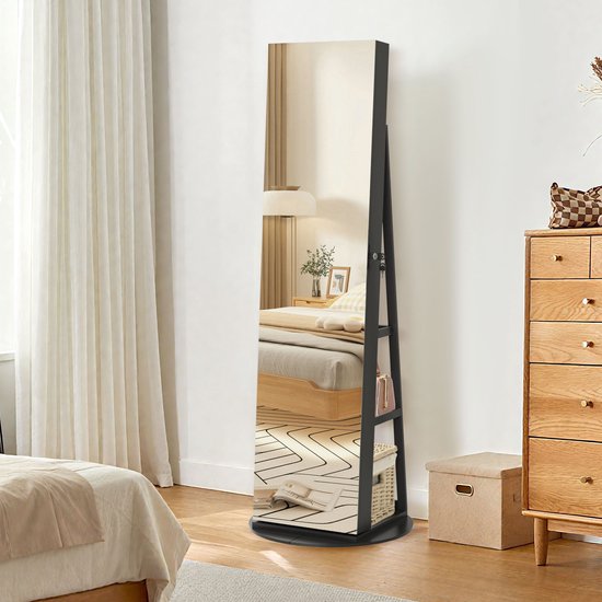 Zwarte staande spiegelkast met opbergvakken aan de zijkant en een spiegel die een slaapkamer reflecteert.