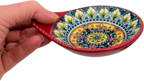 Een rode schaal met een kleurrijk bloemenpatroon wordt in een hand vastgehouden.