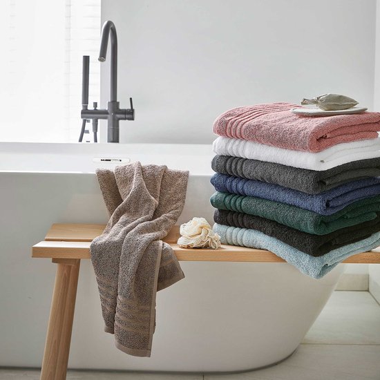 Pile de serviettes colorées, y compris rose, blanc, gris, bleu et vert, près d'une baignoire.