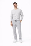 Man met grijze joggingbroek en bijpassende trui met ronde hals, witte sneakers.