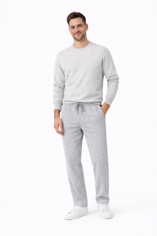 Man met grijze joggingbroek en bijpassende trui met ronde hals, witte sneakers.