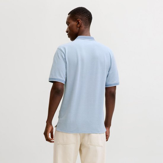 Achterkant man in lichtblauw poloshirt met witte kraag en manchetten, beige broek.