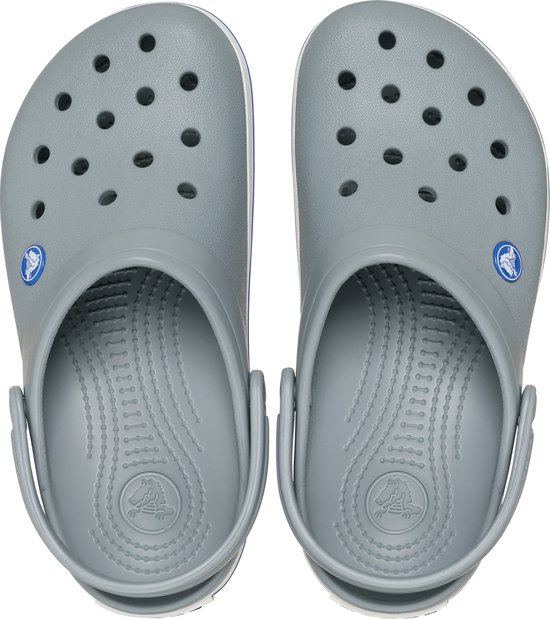 Bovenkant van een paar grijze Crocs met witte en blauwe strepen op de zool.