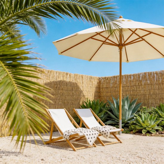 Twee witte ligstoelen met een zwart-wit gestippelde deken onder een crèmekleurige parasol, tegen een bamboe schutting.