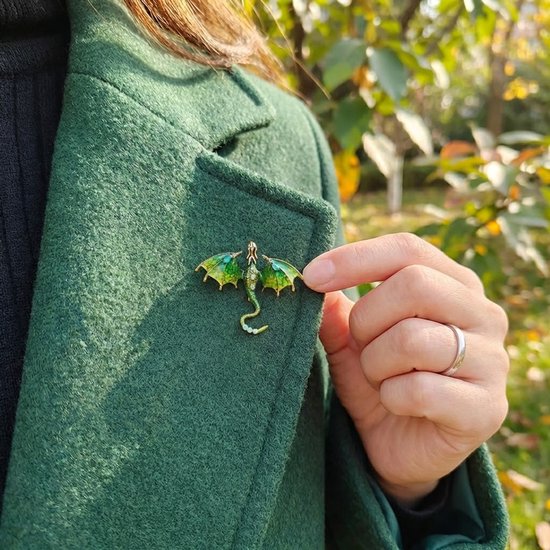 Groene drakenbroche met glinsterende vleugels, gedragen op een groene jas.
