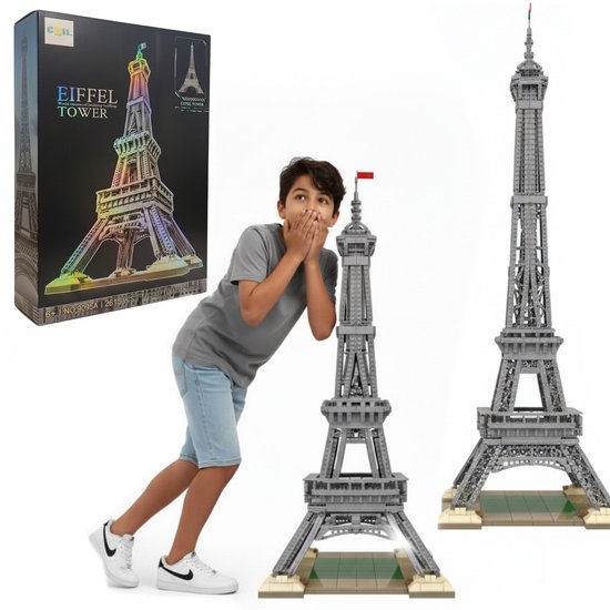 Un garçon regarde avec surprise une grande Tour Eiffel grise en briques de construction, à côté de la boîte.