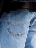 Close-up van de achterzak van een lichtblauwe jeans met decoratieve stiksels.
