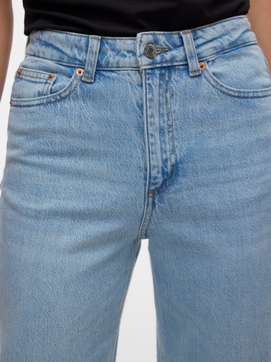 Model van voren gezien in lichtblauwe jeans met een hoge taille en rechte pijpen. Draagt zwarte hakken.