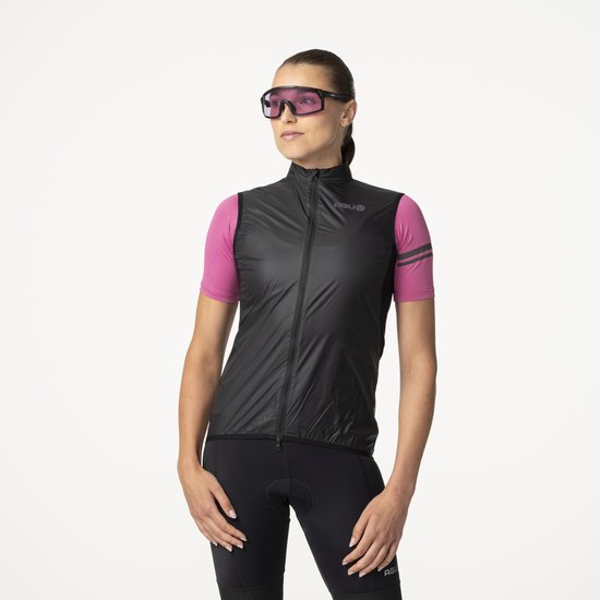 Vrouw in roze fietsshirt en zwarte fietsbroek draagt zwarte bodywarmer en zonnebril.