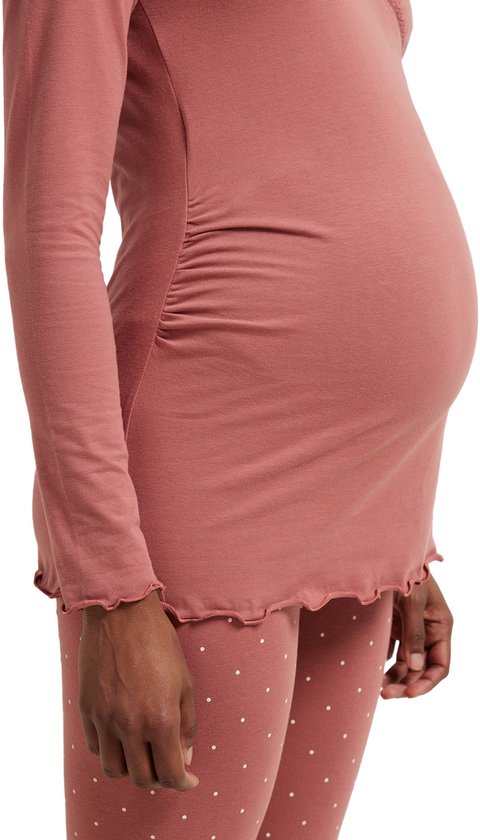 Zij-aanzicht van een zwanger model in een roze wikkelpyjamatop met ruches aan de zijkant en een bijpassende pyjamabroek met stippen.