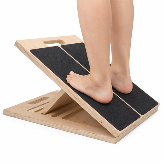 Voeten van een persoon die op een houten balansbord met antislip toplaag staan.