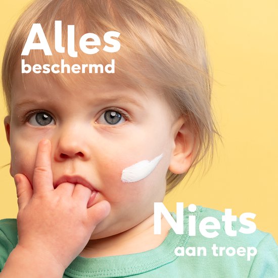 Close-up van een baby met zonnebrandcrème op de wang.