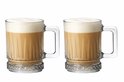Twee glazen bierpullen gevuld met romige koffie en schuim, met verticale ribbels en decoratieve bodem.
