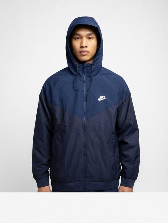 Blauwe Nike windjack met capuchon, tweekleurig design, met witte Nike logo op de borst.