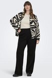 Model met bruin haar, een beige top, een jasje met zebraprint en een zwarte wijde broek.