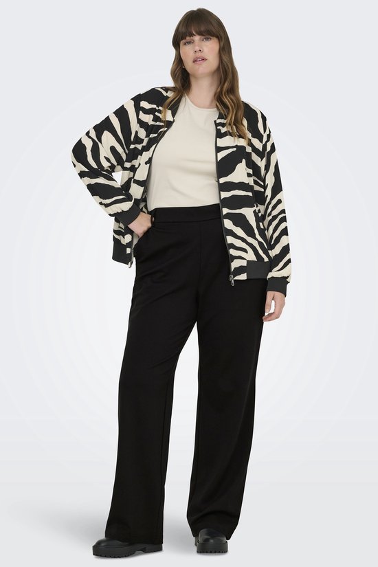 Model met bruin haar, een beige top, een jasje met zebraprint en een zwarte wijde broek.