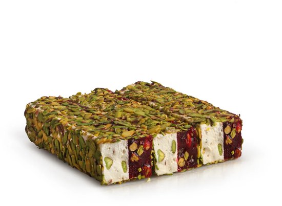 Blok Turkse delicatesse, bedekt met pistachenoten, met witte en rode laagjes.